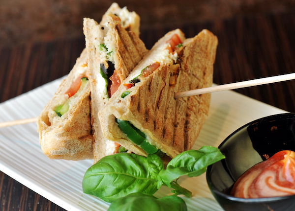 Healthy veggie panini sandwiches, Freshly grilled panini with olives, basil leaves, fresh red and green peppers, tomatoes, and mozzarella cheese served on ciabatta bread with cream ketchup sauce 